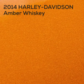 An orange textured color paint swatch with black text in the top-left corner reading '2014 HARLEY-DAVIDSON Amber Whiskey'.